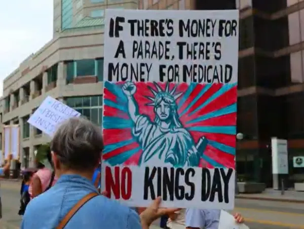 Protester holding sign saying If there's money for a parade there's money for Medicaid