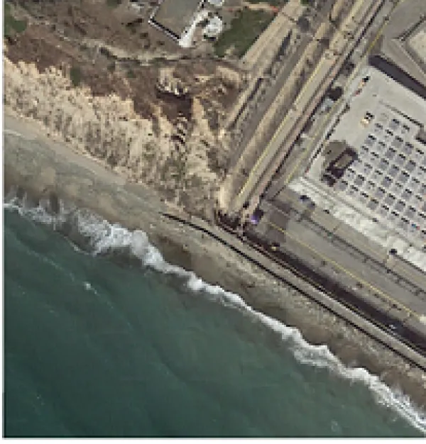 Birds eye view of a beach with ocean waves and a lot of buildings on the coast