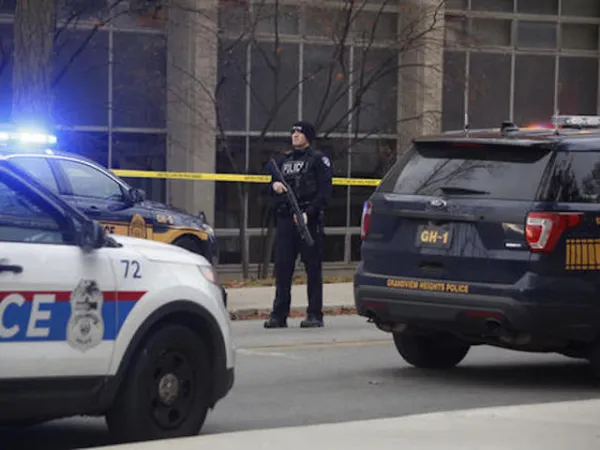 Police car and officer with gun outside building with crime tape around it