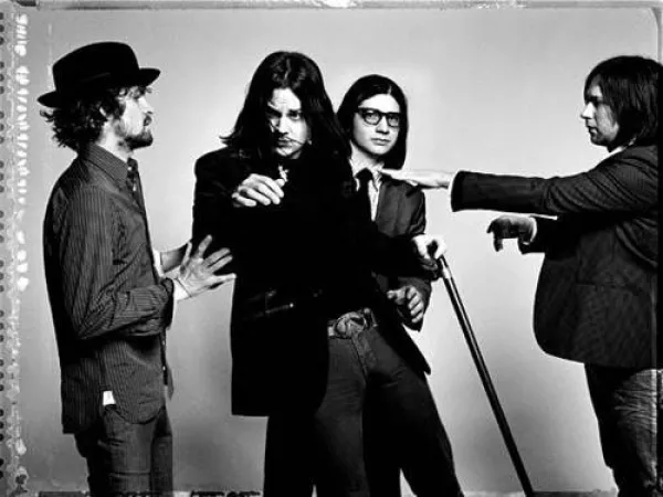 Black and white photo of four white guys in a band with suits on posing like they are moving around funny