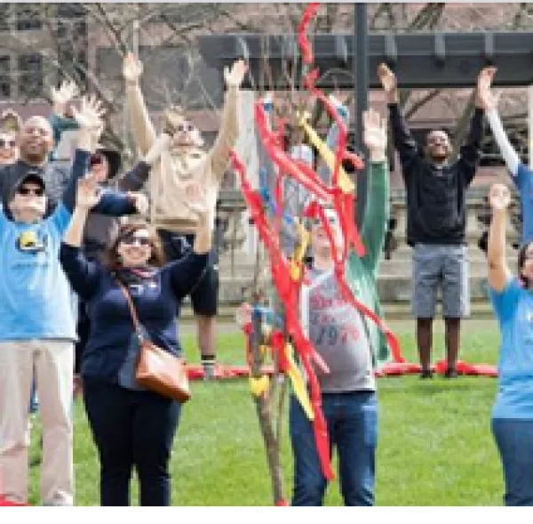 Lots of people outside with hands raised up and colorful streamers falling around