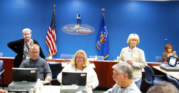People doing a recount at tables with flags in the background