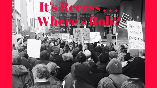 Black and white photo of people at a rally downtown with words It's Recess...Where's Rob?
