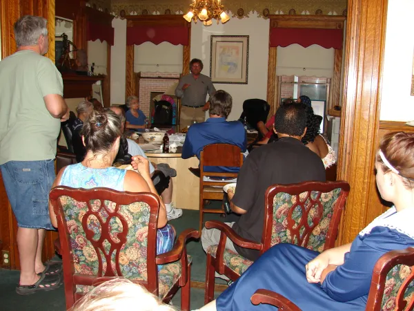 A fancy looking room with people sitting around a table listening to a speaker