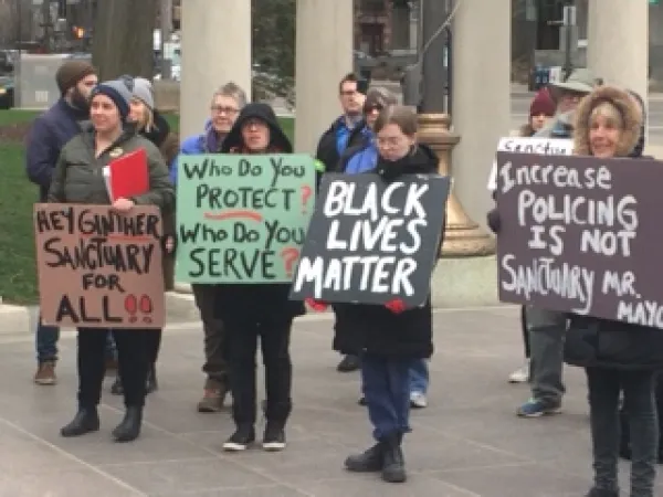 People outside City Hall holding signs 