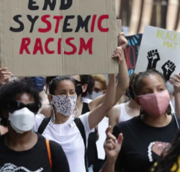 People outside protesting with a sign saying End Systemic Racism
