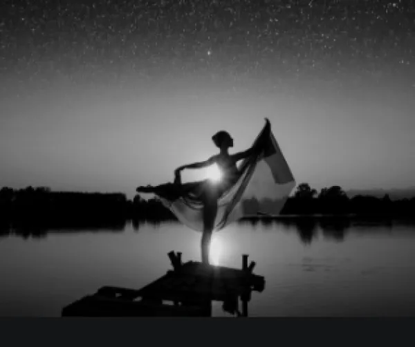 Silhouetted figure of woman posing near a lake and horizon 