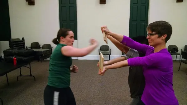 Two women one holding a board and the other one getting ready to karate chop it