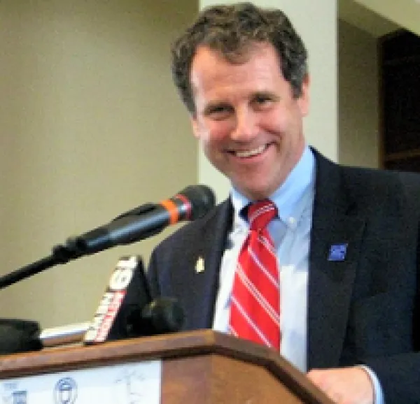 Middle aged white man at a podium smiling