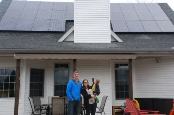 Solar panels on home with man, woman and child out front