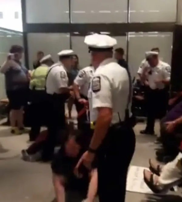 Policeman throwing a woman out of her wheelchair