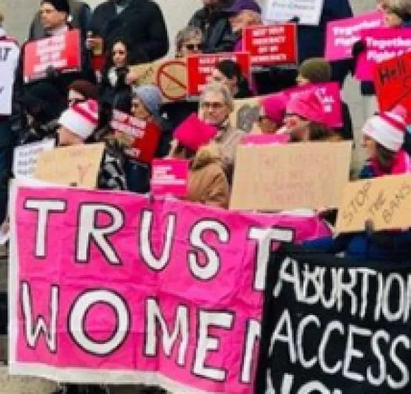 People at a rally holding signs saying Abortion Access and Trust Women