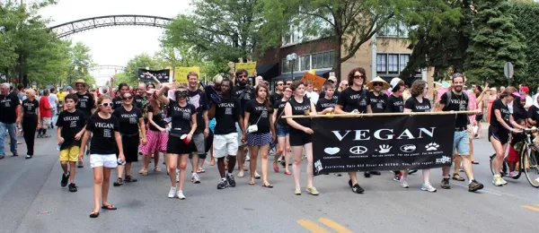 People in black and white Vegan shirts holding Vegan sign marching in parade
