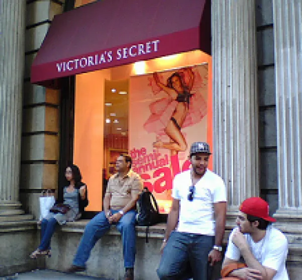 People sitting on a ledge outside a Victoria's Secret store