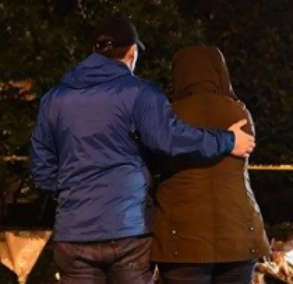 Backs of two people one hugging the other outside