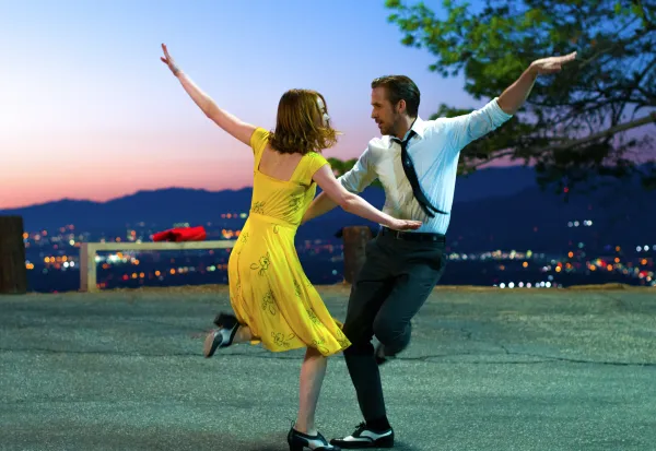 Woman in a yellow dress and man in a shirt and tie dancing wildly
