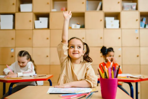 GIrl in classroom raising hand