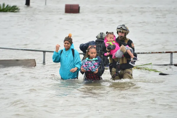 People wading through wasit deep flood
