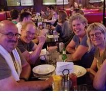 Smiling faces of white middle-aged men and women at a table in a restaurant