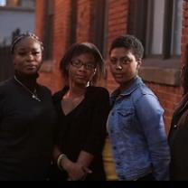 Three black women standing outside a brick building