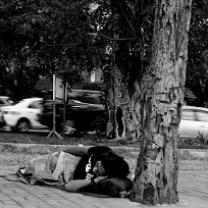 Black and white photo of person lying on the ground under a tree
