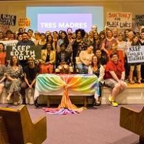 Many people posing inside a church with colorful banners and sign  about Keep Edith Home