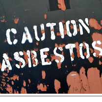 Black and pick mess on a floor and words Caution Asbestos