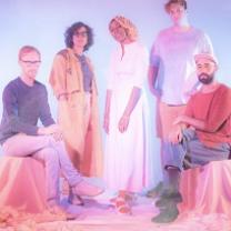 Five people posing two sitting on each side and three standing in the middle