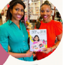 Two smiling women holding up a book