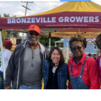 People posing in front of a Bronzeville Growers Market sign