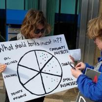 Girl holding sign about how Chase bank makes investments