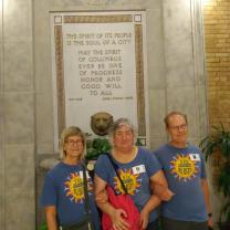 Three people standing in front of etched sign on wall