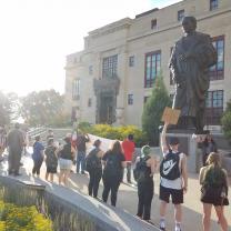 People protesting outside City Hall and large Columbus statue