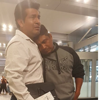 Two Latino men, one hugging the other, looking very sad