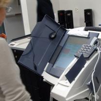 Older woman standing by an electronic voting machine