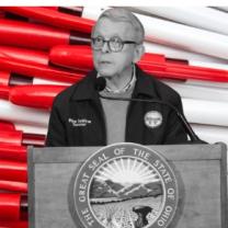Governor Dewine at a podium in front of red pens