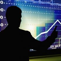 Black silhouette of the back of a man pointing to a bright blue graph that shows a line going up and down