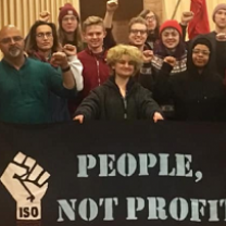 Lots of people posing holding a sign with a fist and words People. Not Profits
