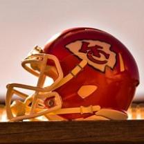 Red football helmet with a YC logo on the side sitting sideways on a wood table
