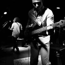 Black/white photo of guy playing a guitar in a band