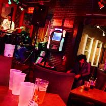 Sideways view of a bar with guy with guitar on stage lighting is very red