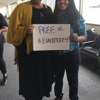 Two people with photo cutting off their heads holding a sign that says Free the Black Pride 4