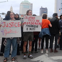 People outside downtown holding signs that say Justice 4 Julius and Columbus Police are murderers Masonique is not