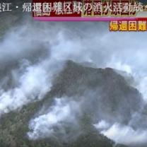 Looking down from sky at lots of smoke on ground with mountains and Japanese writing
