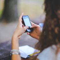 Side view of girl with brown curly hair looking at cellphone