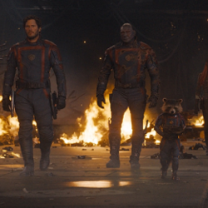 Character walking in formation with fire in the background