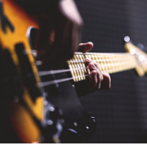 Sideways shot of a person playing a guitar close up of just the guitar and their hands
