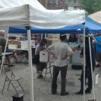 People under outdoor booth tents looking at records