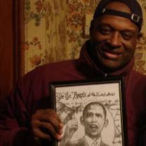 Black man smiling and holding an illustration of Obama
