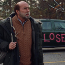 Man with backpack by a car with painting on it saying LOSER